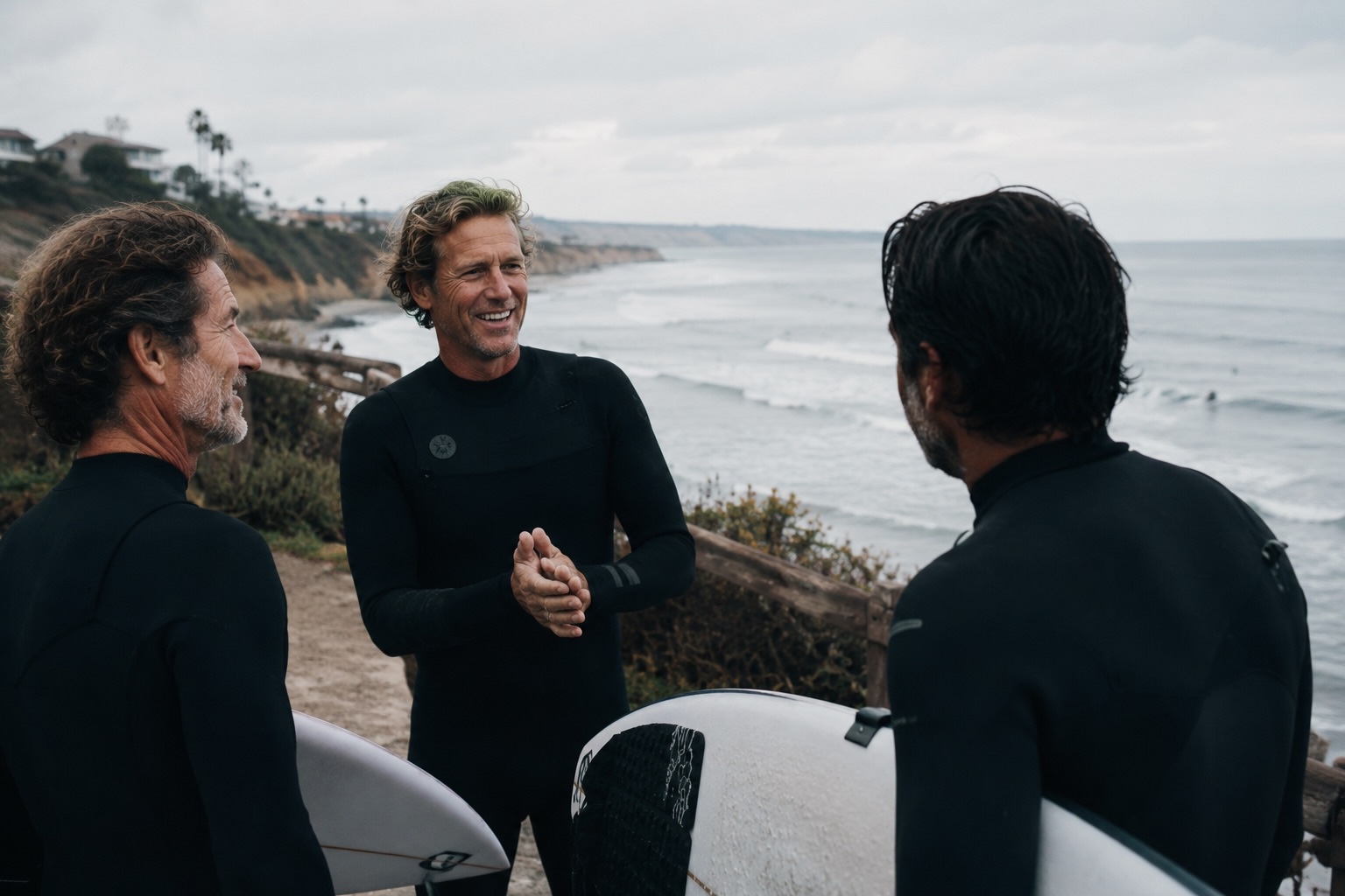 Surfers in wetsuits stopped to talk on the bluff, boards under their arms, the lineup behind them
